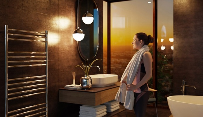 Woman standing in front of mirror in a luzury bathroom with a Vogue towel warmer featured in the foreground